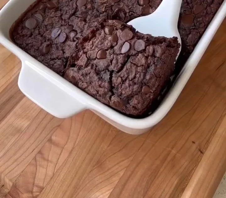 Brownie baked oatmeal topped with chocolate chips and nuts in a rustic bowl