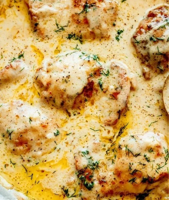 Creamy oven baked chicken thighs served with herbs and spices.