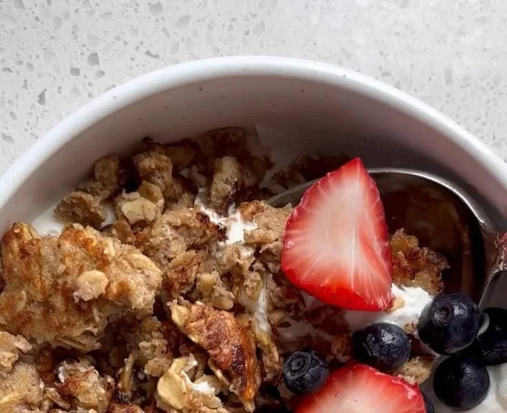 Bowl of creamy scrambled oats topped with fresh fruit and nuts
