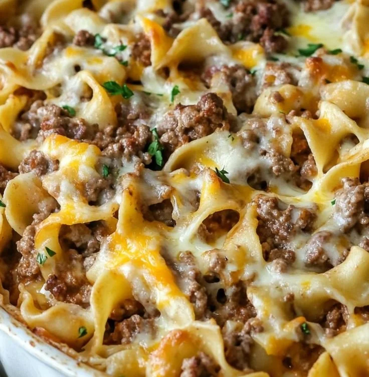 Delicious sour cream beef noodle casserole topped with cheese, garnished with parsley.