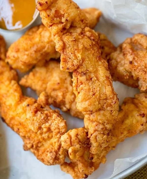 Crispy chicken tenders served with dipping sauce on a plate