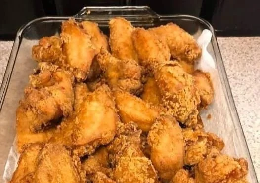 Delicious fried chicken displayed on a glass plate, showcasing its crispy texture.