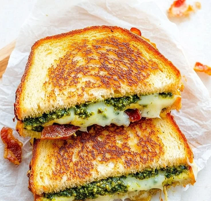 Pesto grilled cheese sandwich with melted cheese and fresh basil pesto