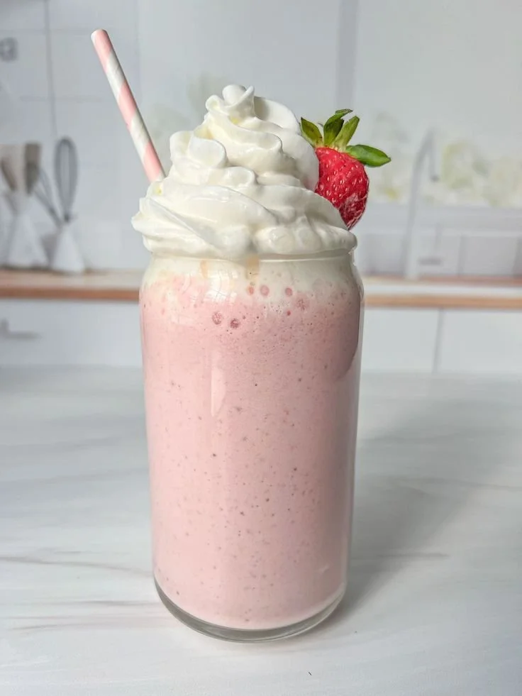 Refreshing strawberry protein shake in a glass with fresh strawberries and protein powder.