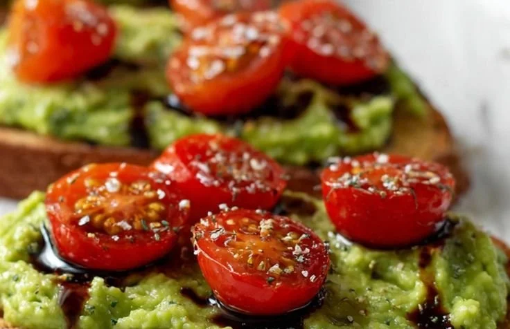 Delicious avocado toast topped with cherry tomatoes on a wooden serving board.
