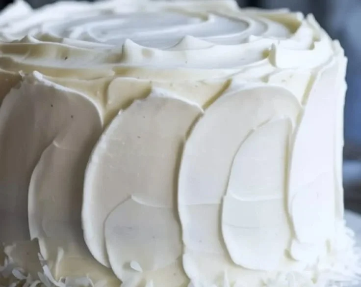 Delicious Coconut Cloud Cake topped with coconut flakes and cream