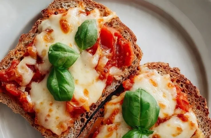 Homemade pizza toast topped with cheese, pepperoni, and herbs.