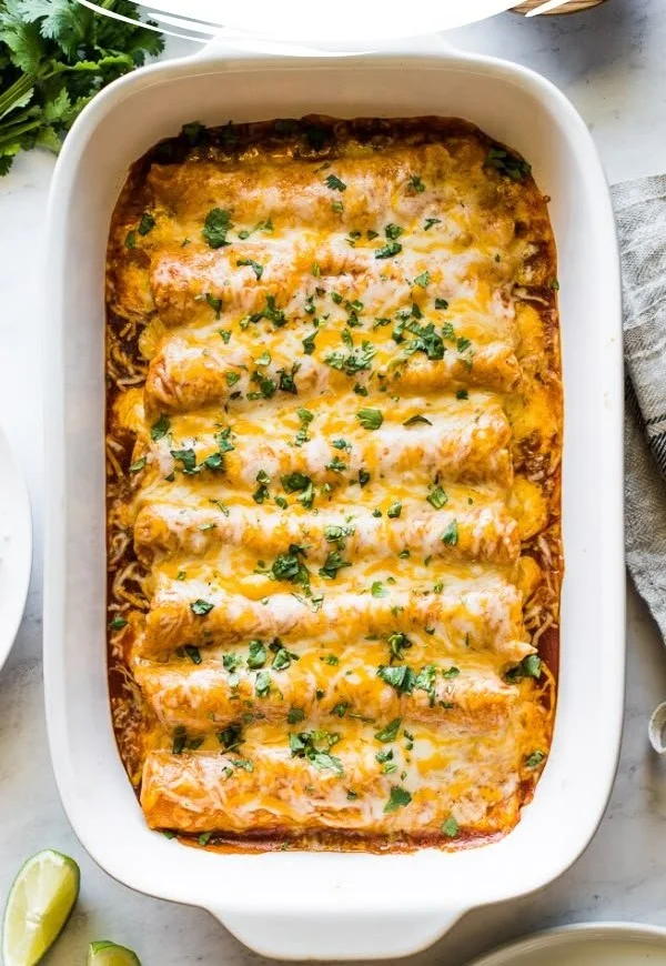 Delicious easy chicken enchiladas topped with cheese and served on a plate.