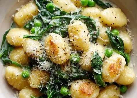 Plate of gnocchi with peas and spinach in creamy sauce