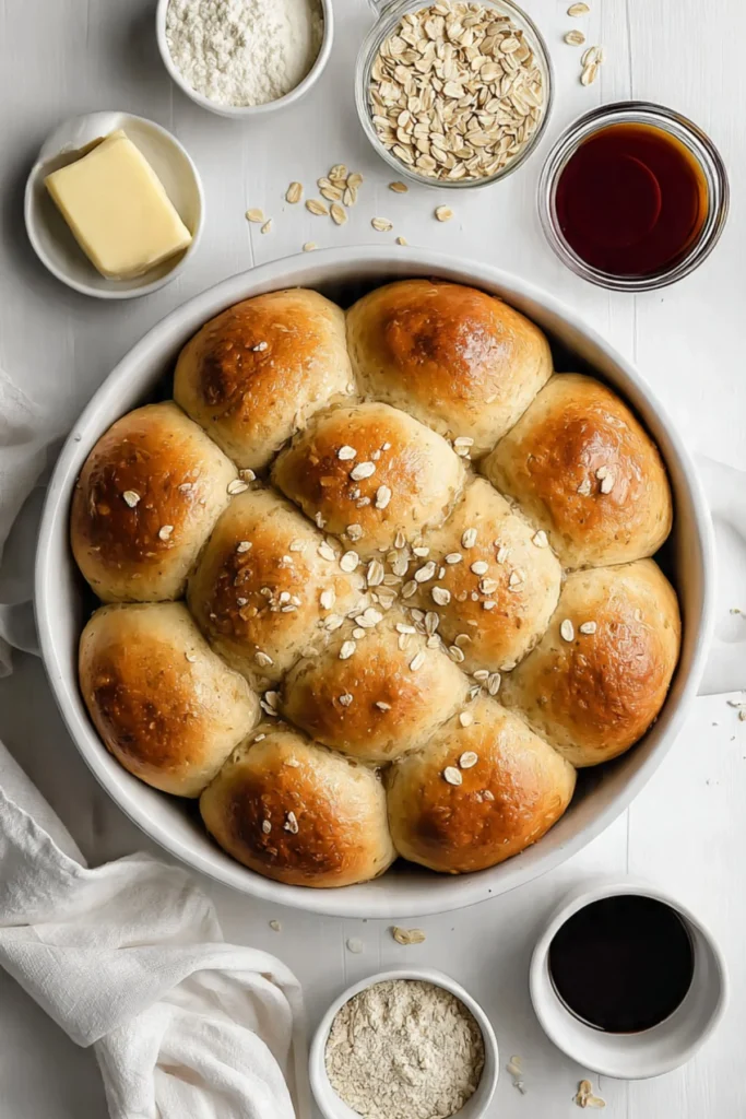 Freshly baked oatmeal molasses dinner rolls on a wooden table.