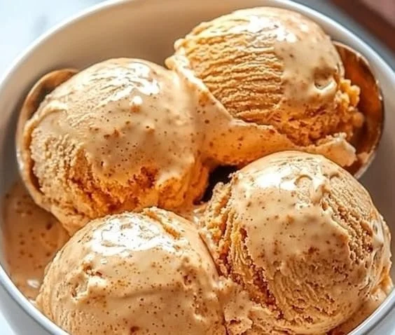 Spiced carrot ice cream served in a bowl with a sprinkle of cinnamon