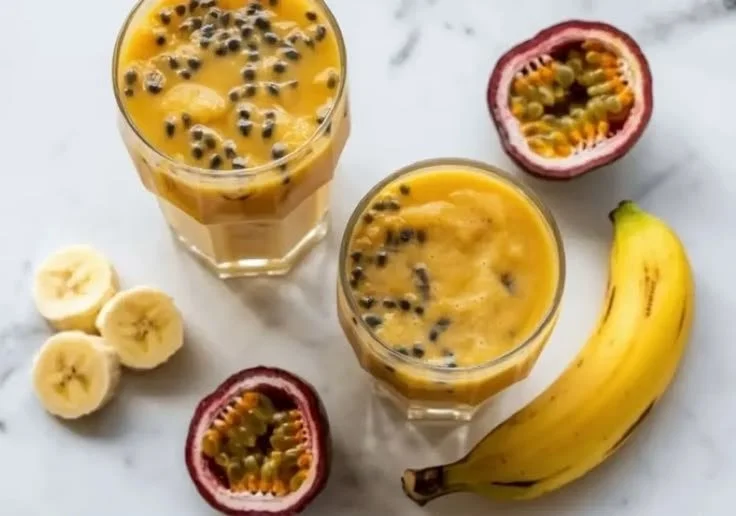 A glass of vibrant passion fruit banana juice garnished with fresh fruit slices.