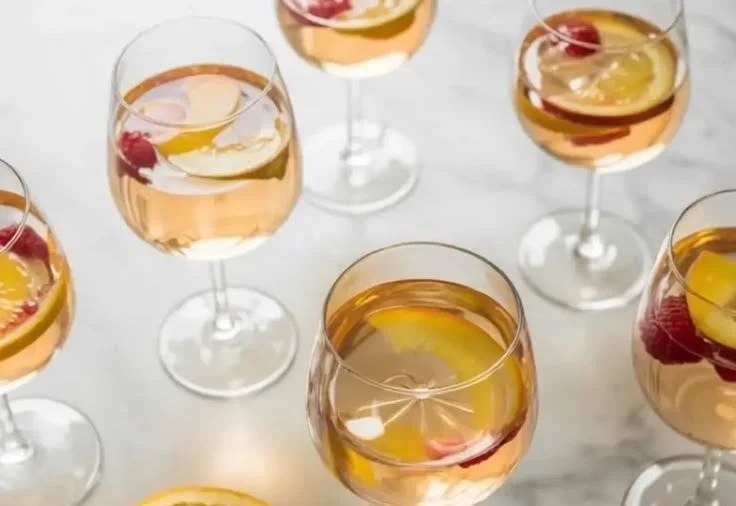 Glass of white peach sangria with fresh peaches and fruit garnish